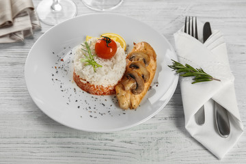 Plate with chicken breast and rice on wooden table