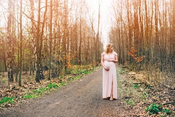 Pregnant woman in dress posing in the forest