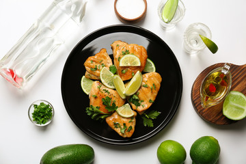 Plate of delicious tequila lime chicken with ingredients on white background