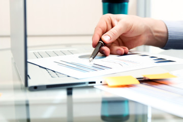 Business man working and analyzing financial figures on a graphs using laptop