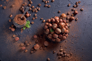 Hazelnut, coffee beans and cocoa powder in dark background.