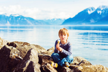 Fototapeta na wymiar Cute little blond boy eating ice cream, resting by lake Geneva, Switzerland