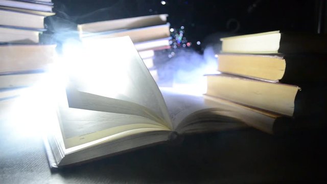 Many old books in a stack. Knoledge concept. Books on a dark background with smoke elements. Bewitched book in center. Glasswatch