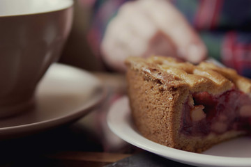 Close-up of female hands, cup of tea and slice of pie. Woman eating cake in cafe