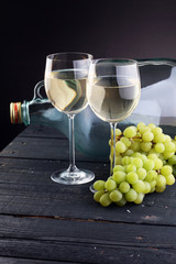 Bottle and glass of white wine, grape on wooden table