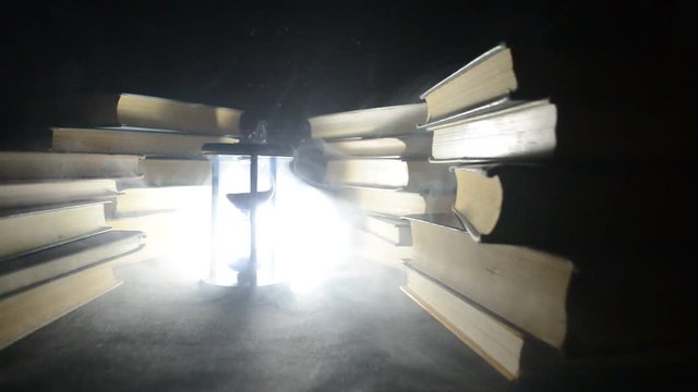 Many old books in a stack. Knoledge concept. Books on a dark background with smoke elements. Bewitched book in center. Glasswatch
