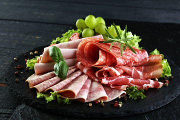 Food tray with delicious salami, pieces of sliced ham, sausage, tomatoes, salad and vegetable - Meat platter with selection