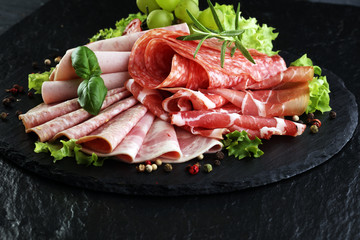 Food tray with delicious salami, pieces of sliced ham, sausage, tomatoes, salad and vegetable - Meat platter with selection