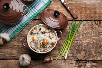 Tasty rice with chicken in saucepan on wooden table