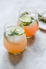 glass of fresh juice with lime and rosemary on stone table background