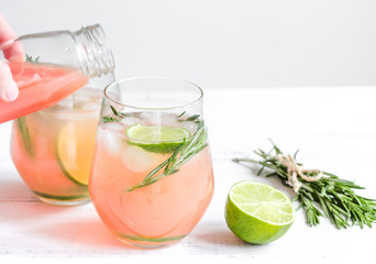 sliced lime, rosemary, juice in glass and bottle on white table background