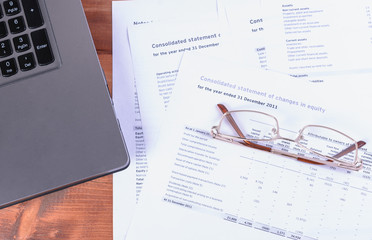 Financial statements, glasses and laptop on the table