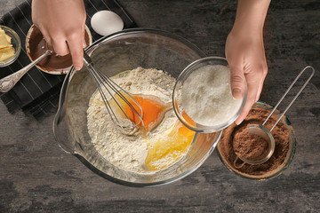 Woman preparing dough for cocoa brownies on table