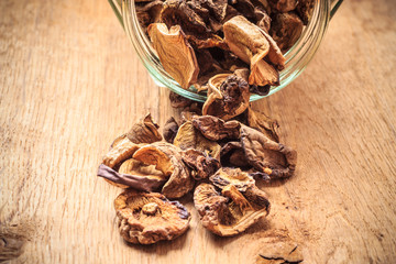 Dry mushrooms in jar on wooden table.