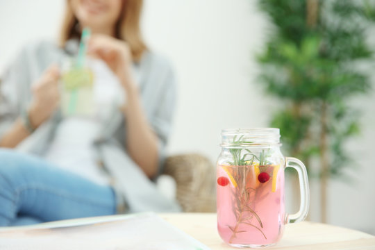 Jar of fresh lemonade and blurred woman on background