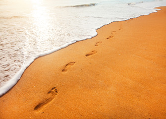 beach, wave and footprints at sunset time