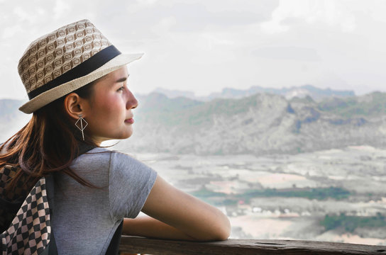 Woman traveler looks at the edge of the cliff on the mountains hi