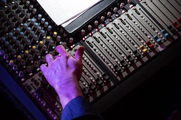 Sound mixer. Professional audio mixing console with lights, buttons, faders and sliders. With hand