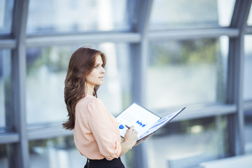 Fototapeta premium successful business woman with financial documents standing near a large window in a modern office