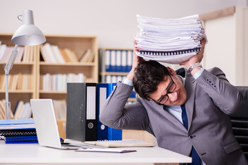 Businessman struggling with stacks of papers