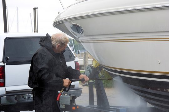 Caucasian man pressure washing a boat hull