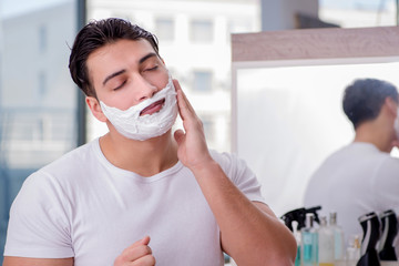 Young handsome man shaving in the morning