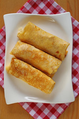  Stuffed pancakes on a white rectangular plate On a checkered red white cotton napkin