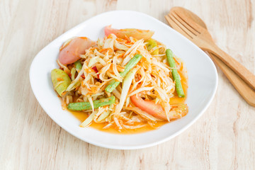 Papaya salad in a white plate on a wooden table,Local thai food