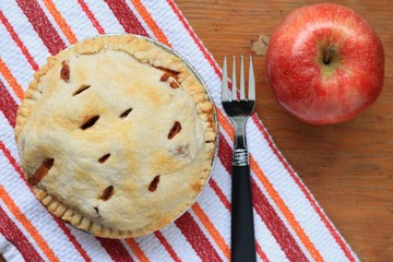 Freshly baked apple pie displayed with an apple and fork.