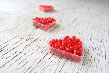 Red cinnamon hearts displayed in heart containers.