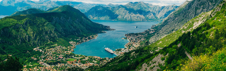 Bay of Kotor from the heights. View from Mount Lovcen to the bay. View down from the observation platform on the mountain Lovcen. Mountains and bay in Montenegro. The liner near the old town of Kotor. - obrazy, fototapety, plakaty