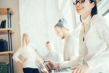 Obraz premium Young business team working in loft office. Handsome woman and man with stubble using laptops. Marketing department researching new digital plan together