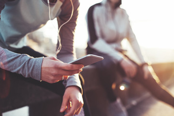 Two athletes practicing sport on the street. Woman using mobile phone. Man resting after exercise