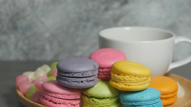 panning shot of white cup of hot coffee and colorful macaroons dessert food on dish