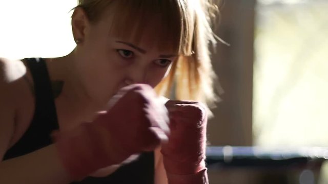 Female boxer finishing workout with punching bag, overcoming emotional stress