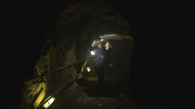  Team of potholers exploring underground cave, focus on woman at the front