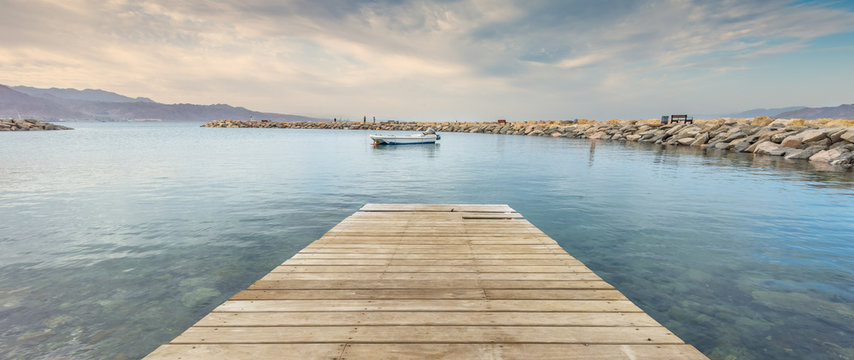 Wooden footpath among marine lagoon and stone public walking pier in Eilat - famous resort city in Israel