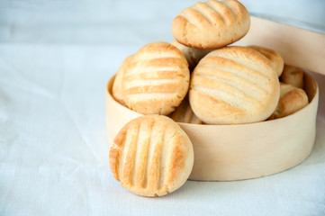 Close up of  heap of freshly baked rice flour ginger cookies in a wooden box on a white tablecloth. Copy space.