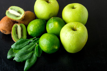 Ingredients for smoothie. Green fruits on black wooden background. Apple, lime, spinach, kiwi. Detox. Healthy food.