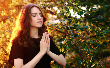 The girl prays in nature. eyes closed.