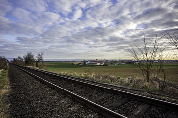 Fototapeta na wymiar Schienen in den Feldern Rheinhessens unter einem bedeckten Himmel