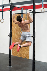 Athletic man doing pull ups in gym