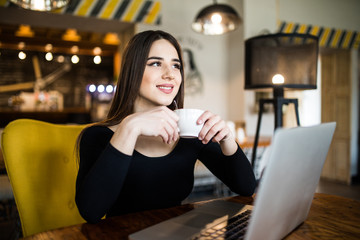 Cheerful woman using laptop and drink coffee