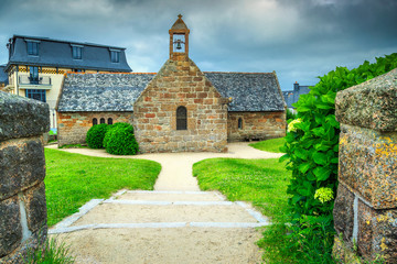 Fototapeta na wymiar Old stone church with flowered entrance in Brittany region, France
