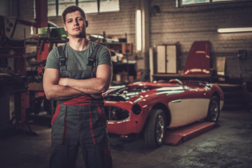 Obraz na płótnie Canvas Mechanic in classic car restoration workshop
