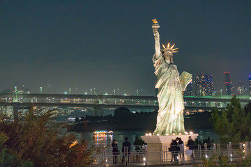 Fototapeta premium Statue of Liberty with Rainbow Bridge, Tokyo Tower and Tokyo City in Background at Night