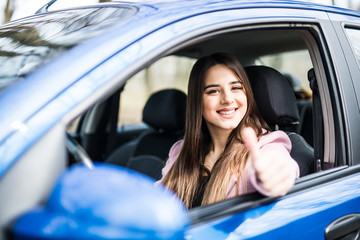 happy beauty young woman is showing a thumb from a car