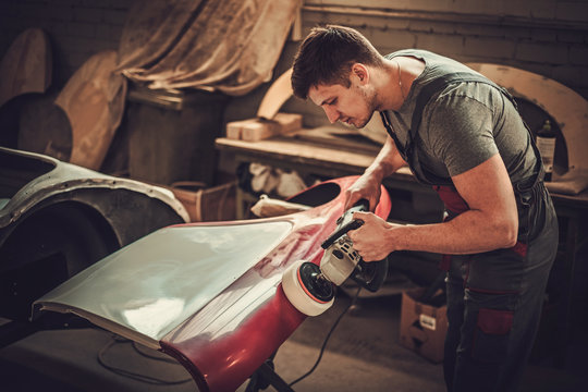 Mechanic polishning car body details in restoration workshop