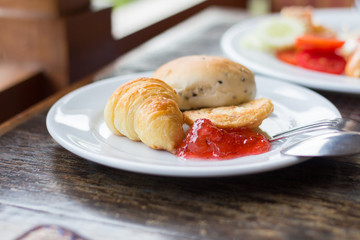 Fresh Croissants with strawberry jam on rustic wooden background. Selective focus