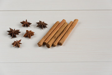 Cinnamon sticks and star anise on white wooden background.